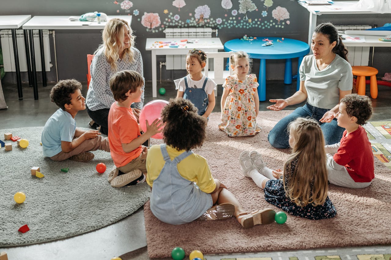 services-02 Children in circle time with teachers, engaging in a kindergarten classroom activity.