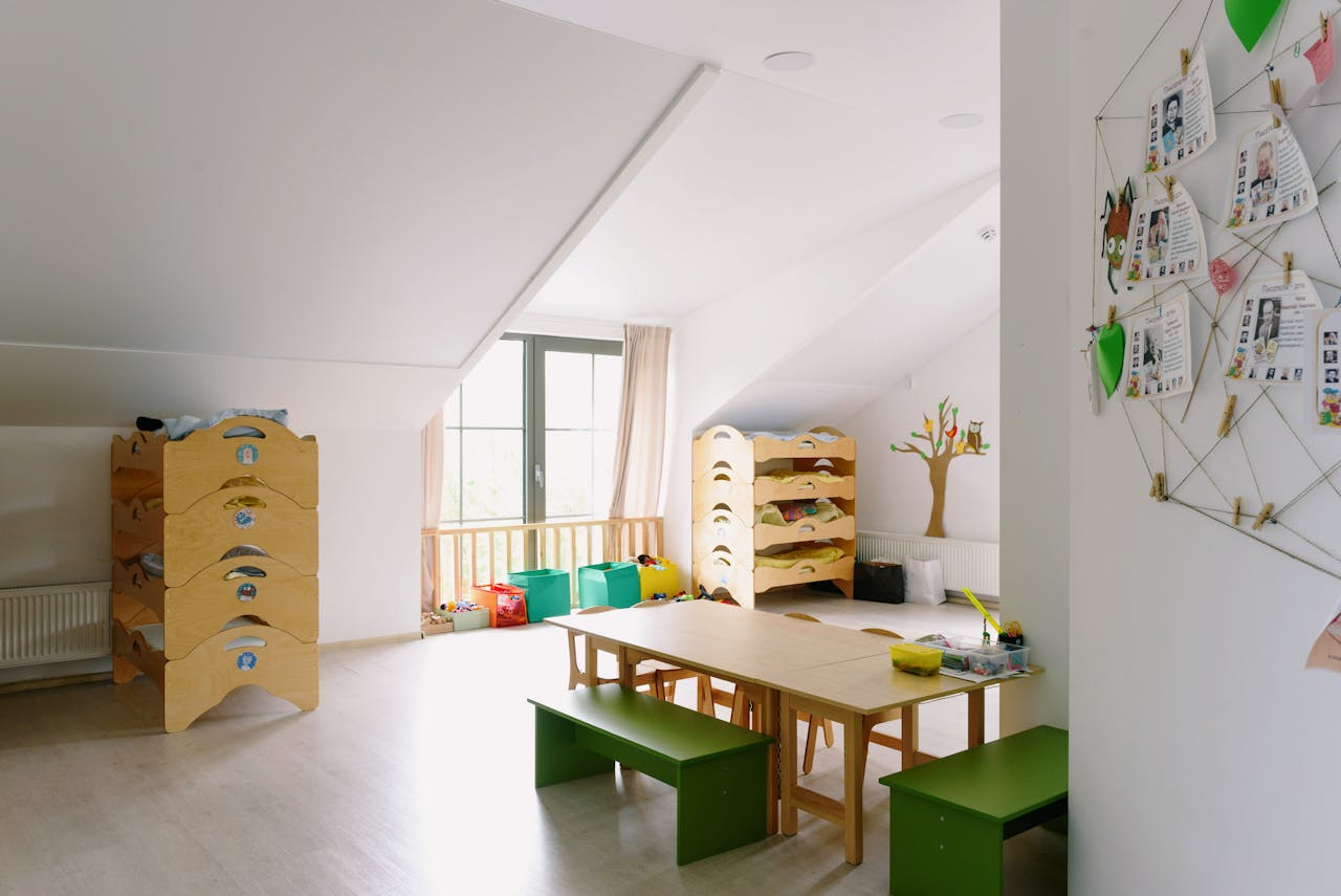 home-hero A well-lit and organized kindergarten room with wooden furniture and playful decor.